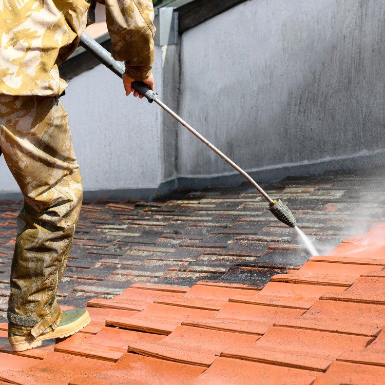Person using power washer to clean orange tile surface